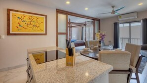 A modern dining area with a glass-top table, chairs, and a view of a balcony. - Dog-friendly Apartment With Rooftop Infinity Pool, Gym, Central AC & Balcony (Cabo San Lucas)