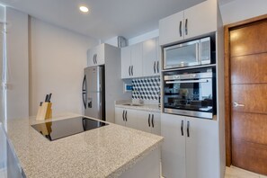 Una cocina moderna con gabinetes blancos, electrodomésticos de acero inoxidable y una encimera negra.