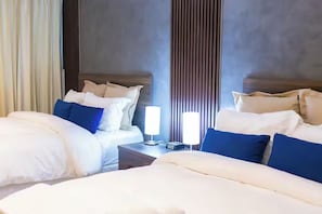Hotellihuone, jossa on kaksi sänkyä, yöpöytä lampun kanssa ja seinä, jossa on pystysuoria viivoja.