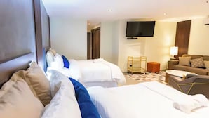 Ett hotellrum med två sängar, en soffa, en tv och ett litet bord.