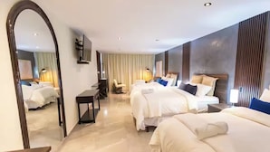 A hotel room with a large mirror, a desk, two beds, and a view of the room through the mirror.