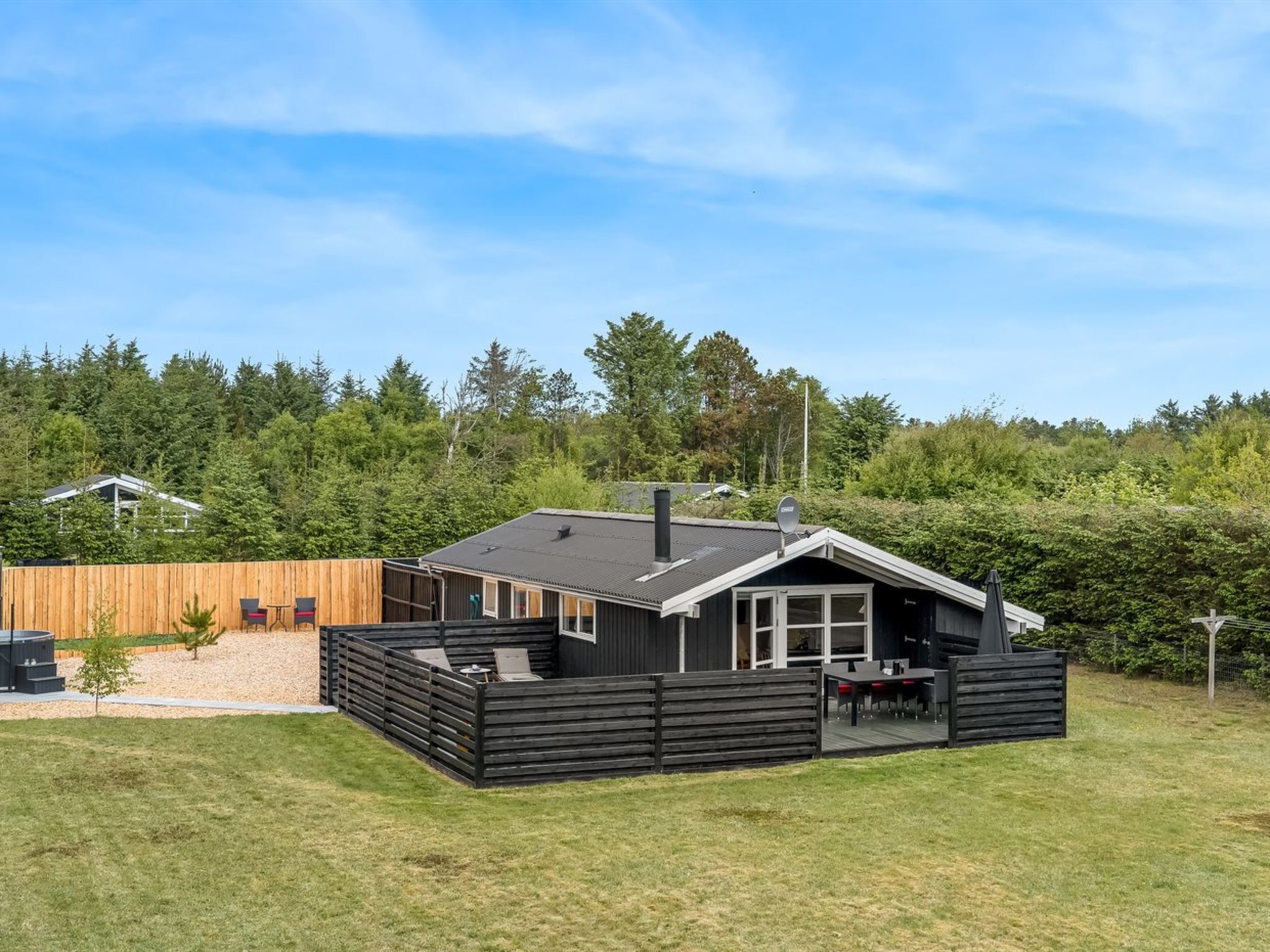 A modern house with a deck, a chimney, and a satellite dish.