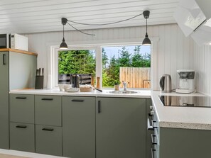 Eine moderne Küche mit großem Fenster, einer Kaffeemaschine und einem Wasserkocher.