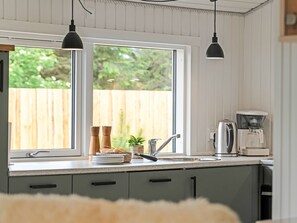 Eine Küche mit Fenster, einer Kaffeemaschine und einem Spülbecken.