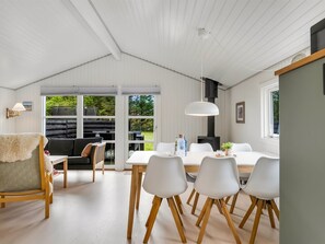 Ein modernes Interieur mit Essbereich, weißen Möbeln und einem großen Fenster.