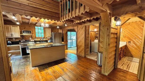 A spacious kitchen with wooden floors, a central island, and built-in appliances.