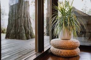 A wooden deck, a large tree, and a potted plant with a woven base.
