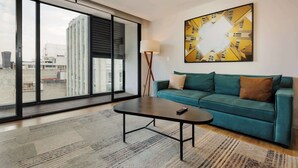 A modern living room with a sofa, a coffee table, a floor lamp, and a large abstract painting on the wall. - w* | Upscale 1BR w/ AC in the Heart of Roma Sur (Ciudad de México)