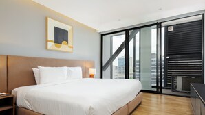 A modern hotel room with a large bed, a nightstand, a wall-mounted lamp, and a city view through floor-to-ceiling windows. - w* | Upscale 1BR w/ AC in the Heart of Roma Sur (Ciudad de México)