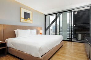 A modern hotel room with a large bed, a nightstand, a wall-mounted lamp, and a city view through floor-to-ceiling windows. - w* | Upscale 1BR w/ AC in the Heart of Roma Sur (Ciudad de México)