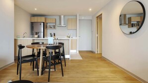 A modern kitchen with a dining area, wooden cabinets, a stainless steel refrigerator, and a microwave. - w* | Upscale 1BR w/ AC in the Heart of Roma Sur (Ciudad de México)