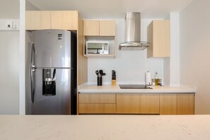 Eine moderne Küche mit Edelstahl-Kühlschrank, Mikrowelle und Holzschränken.