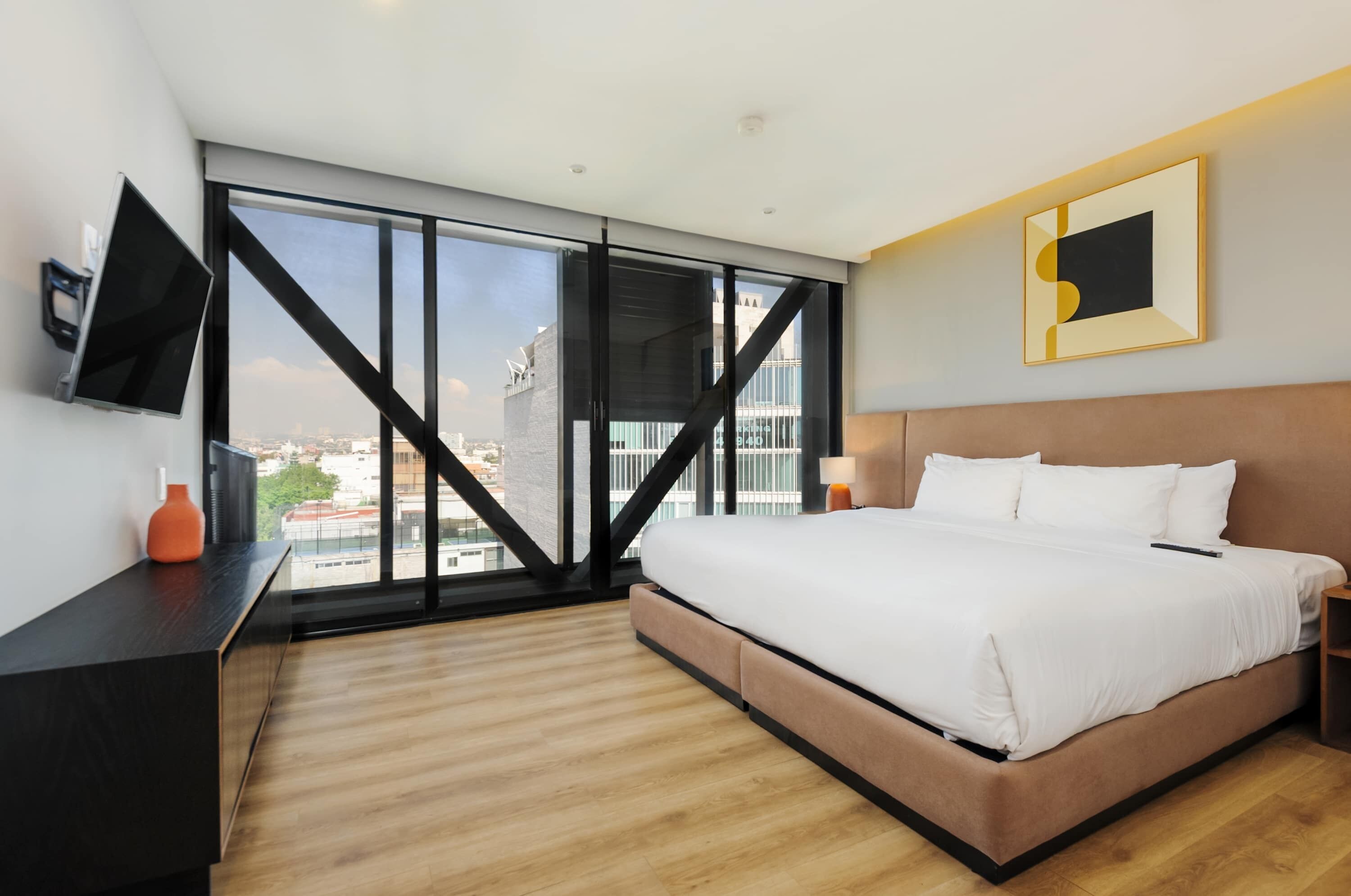 Een moderne hotelkamer met een groot bed, een flatscreen televisie en uitzicht over de stad.