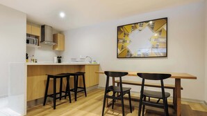 Uma cozinha moderna com área de bar, banquetas de madeira e uma mesa de jantar.