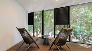 A room with two wicker chairs, a small round table, and large windows with black shutters. - w* | Stylish 2BR w/ AC in the Heart of Roma Sur (Ciudad de México)