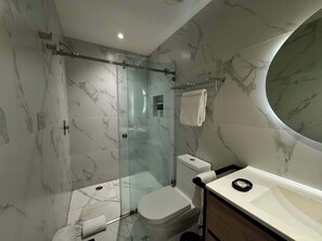 Ein modernes Badezimmer mit einer gläsernen Dusche, einer Toilette, einem Waschbecken und einem Waschtisch.