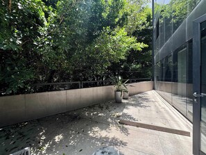 Ein modernes Gebäude mit Glasfassade, einem Betonpflanzkübel mit Topfpflanze und einer gefliesten Terrasse.