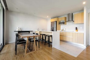 A modern kitchen with a central island, bar stools, and a dining table. - w* | Charming 1BR w/ AC in the Heart of Roma Sur (Ciudad de México)