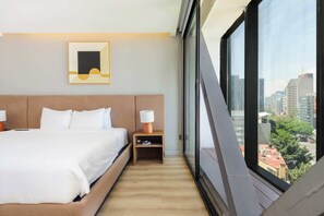 A hotel room with a bed, bedside table, lamp, and a city view through large windows. - w* | Stunning 1BR w/ AC in the Heart of Roma Sur (Ciudad de México)