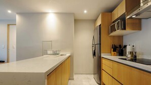 A modern kitchen with a large island, stainless steel appliances, wooden cabinets, and a marble countertop. - w* | Stunning 1BR w/ AC in the Heart of Roma Sur (Ciudad de México)