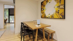 Ein moderner Essbereich mit einem Holztisch, schwarzen Stühlen und einem großen abstrakten Gemälde an der Wand.