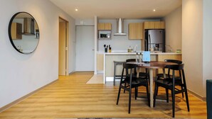 Eine moderne Küche mit Essbereich, Holzboden und einem runden Spiegel an der Wand.