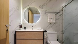 Ein modernes Badezimmer mit Marmorwaschtisch, Toilette und einer Duschkabine aus Glas.
