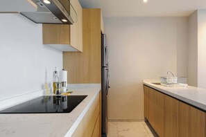 Eine moderne Küche mit eingebautem Herd, Holzschränken und einem Edelstahl-Kühlschrank.