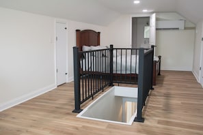 A bedroom with a wooden bed, a black metal railing, a white door, and a white air conditioning unit.