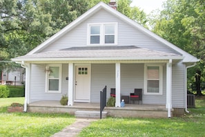 A single-story house with a front porch, a door, and two windows.