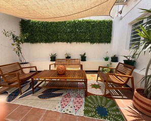 Eine Terrasse mit Holzmöbeln, einem Tisch und Topfpflanzen.