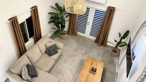 A living room with a sofa, coffee table, and hanging rattan lamps. - Front Street Gem - Steps to Beach & Shopping (Philipsburg)