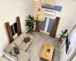 Ein Wohnzimmer mit einer Couch, einem Couchtisch und hängenden Rattanlampen.