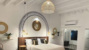 A bedroom with a bed, bedside tables, a hanging light fixture, and a mirror on the wall. - Front Street Gem - Steps to Beach & Shopping (Philipsburg)