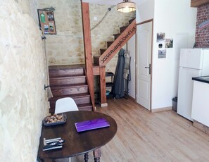 A kitchen with a wooden staircase, a dining table with a basket of nuts, and a refrigerator. - Lo Gîte à l'Ocest, la Grange de la Fontaine St Georges - 15 Km from Sarlat (Saint-Cirq-Madelon)