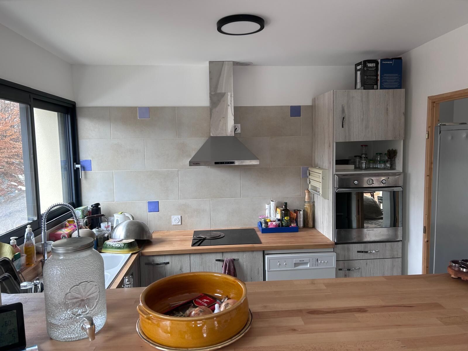 Een moderne keuken met een fornuis, oven en een groot raam.
