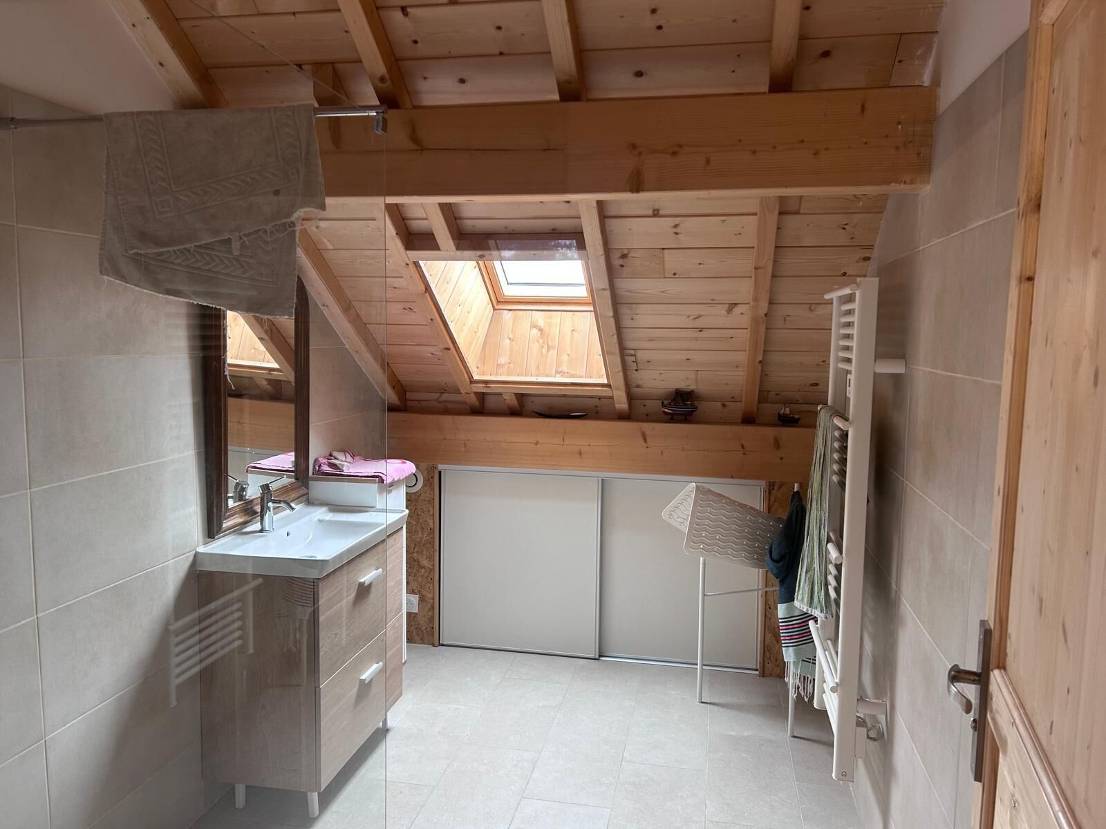 Een kleine badkamer met dakraam, een wastafel en een handdoekrek.