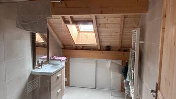 Een kleine badkamer met dakraam, een wastafel en een handdoekrek.