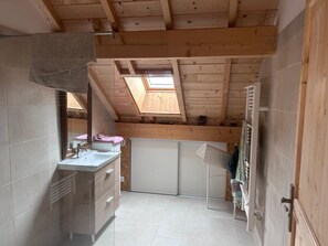 Une petite salle de bain avec un puits de lumière, un lavabo et un porte-serviettes.