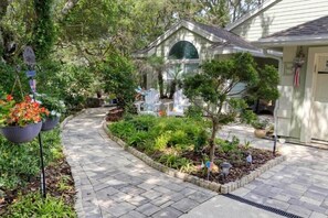 Ein Wohnhaus mit befestigter Auffahrt, einem kleinen Garten mit verschiedenen Pflanzen und einem Giebeldach sowie einem Eingangsbereich.