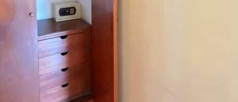 Un pasillo con piso de madera, un armario, una pequeña mesa con un reloj y un cuadro en la pared.
