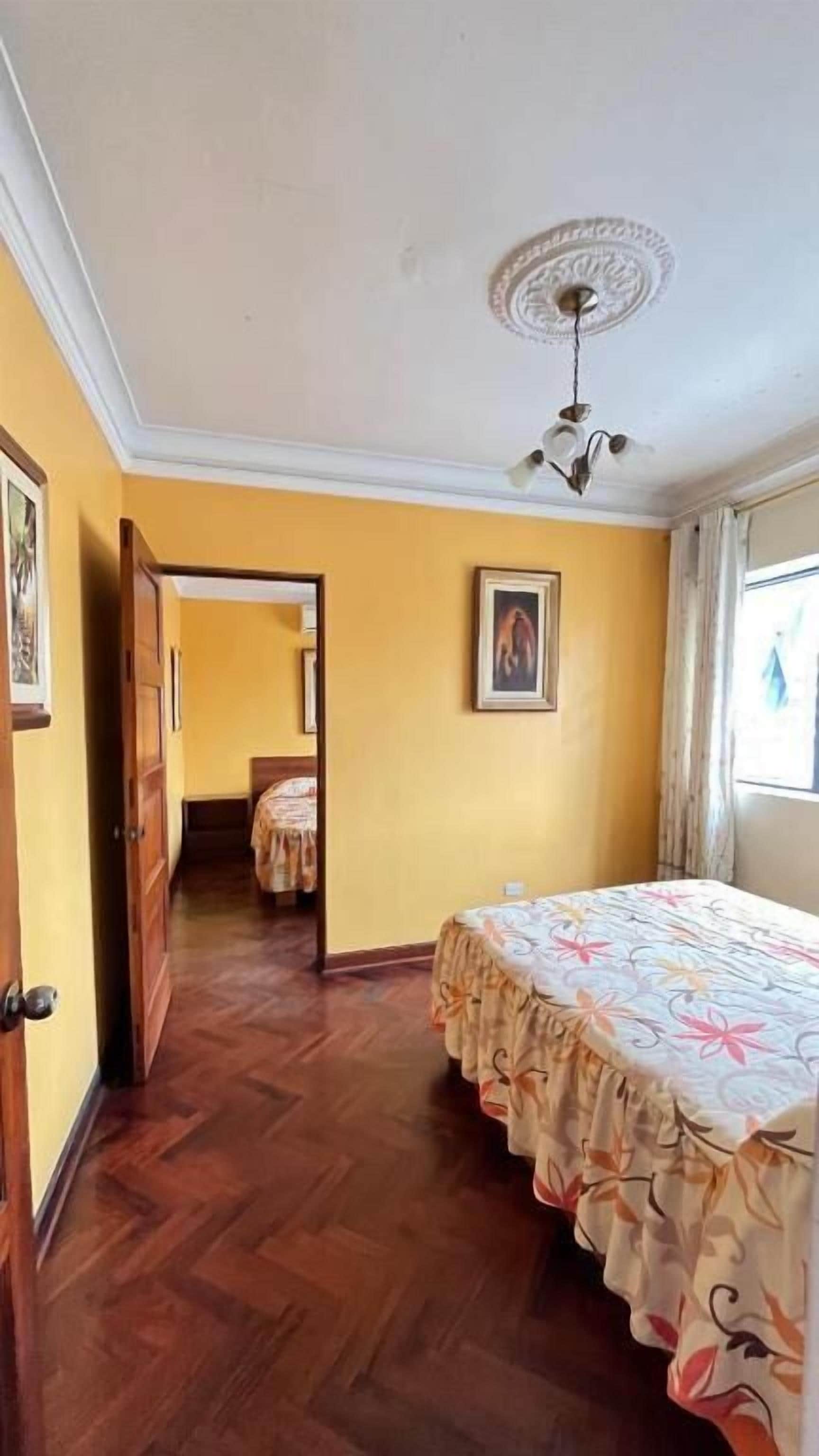 Una habitación con cama, ventilador de techo, puerta y ventana.