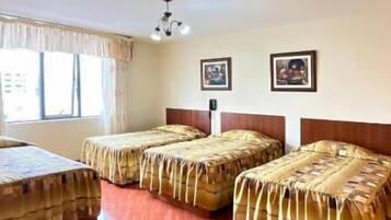 Una habitación con una cama grande, dos camas más pequeñas, una ventana con cortinas y una lámpara en el techo.