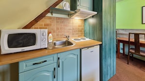 A compact kitchen with a microwave, stove, sink, and a small refrigerator. - Roky - Dolní náměstí by Interhome (Rokytnice nad Jizerou)
