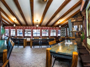 Ein Restaurant mit Holzbalken, Fliesenböden und Blick auf parkende Autos.