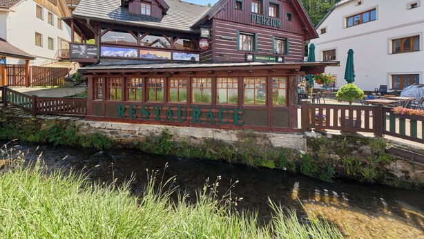 A restaurant with a wooden facade, a balcony, and a view of a stream. - Roky - Dolní náměstí by Interhome (Rokytnice nad Jizerou)