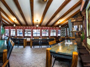 Ein Restaurant mit Holzbalken, Fliesenböden und Blick auf parkende Autos.