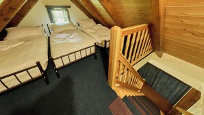 A loft bedroom with two beds, a wooden staircase, and a window. - Roky - Dolní náměstí by Interhome (Rokytnice nad Jizerou)