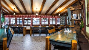 Ein Restaurant mit Holzbalken, Fliesenböden und Blick auf parkende Autos.