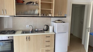 Una cocina con armarios de madera, estufa, refrigerador y pileta.